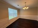 Elegant dining room featuring classic wainscoting, dark wood floors, and a stylish chandelier at 330 Kentwood Springs Dr, Hampton, GA 30228
