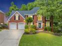 Charming two-story red brick home boasts a three-car garage and lush landscaping at 10400 Groomsbridge Rd, Alpharetta, GA 30022