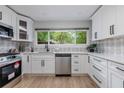 A well-lit kitchen with new stainless steel appliances, white cabinets and view to the yard at 2012 Variations Ne Dr, Atlanta, GA 30329