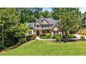 Two-story brick home boasts a lush green lawn, mature trees, and elegant architectural design at 1311 Cobblemill Nw Way, Kennesaw, GA 30152