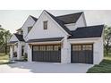 Angle view of a two-car garage with carriage doors, black trim windows, and a white brick facade at 3629 Centerville Rosebud Rd, Snellville, GA 30039
