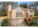 Angle view of exterior showing stone accents, garage, and wooden front stairs surrounded by mature trees and landscaping at 3032 Ross Rd, Snellville, GA 30039