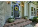 Inviting front entrance with a decorative wreath, brick steps, and elegant potted plants at 1328 Amberwood Dr, Woodstock, GA 30189