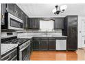 Kitchen featuring wood floors, stainless steel appliances, granite countertops and black cabinets at 1822 Oriole Trl, Lithia Springs, GA 30122