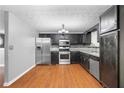 Kitchen featuring wood floors, stainless steel appliances, granite countertops and black cabinets at 1822 Oriole Trl, Lithia Springs, GA 30122