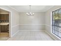 This dining room features neutral colored walls, tile flooring, modern lighting, and natural light from the window at 6429 Woodstone Way, Morrow, GA 30260