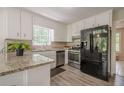 Bright kitchen with stainless steel appliances, granite countertops, white cabinets, and wood-look flooring at 2071 Arrowhead Trl, Marietta, GA 30062