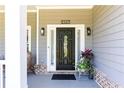 Inviting front porch with a stylish black door, decorative plants, and charming brick accents at 2167 Tilson Rd, Decatur, GA 30032