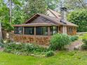 Cozy bungalow with wood shingles, stone chimney, and screened porch surrounded by greenery at 4624 Park Dr, Pine Lake, GA 30072