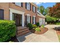 Inviting front entrance with a well-maintained walkway, brick steps, trimmed shrubbery, and a black front door with wreath at 1661 Duxbury Nw Ln, Kennesaw, GA 30152