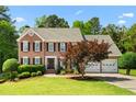 Charming two-story brick home featuring a landscaped yard, two-car garage, and classic architectural details on a sunny day at 1661 Duxbury Nw Ln, Kennesaw, GA 30152