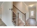 Welcoming entryway featuring hardwood floors, staircase with dark metal spindles, and a bright white door with glass panes at 408 Westmarch Cir, Loganville, GA 30052