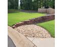Picturesque backyard featuring a stone retaining wall and lush green grass at 6210 Douglas Manor Ct, Douglasville, GA 30134