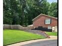 Spacious backyard showcasing a well-maintained lawn, brick retaining wall, and privacy fence at 6210 Douglas Manor Ct, Douglasville, GA 30134