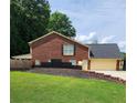 Home featuring a garage, driveway, brick exterior, a dark roof, and green lawn at 6210 Douglas Manor Ct, Douglasville, GA 30134