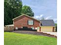 Back exterior of brick home, featuring a two-car garage and a lush green lawn at 6210 Douglas Manor Ct, Douglasville, GA 30134