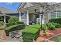 Inviting front porch with stone steps, manicured hedges, and classic white pillars and railings at 595 Stonepark Ln, Suwanee, GA 30024