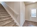 Carpeted staircase with a white railing next to an entry door, offering a welcoming entrance at 4554 Eastbrook Pl, Snellville, GA 30039