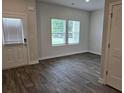 Cozy living room with hardwood floors, two windows, and a white door with blinds at 1669 Fuma Leaf Way, Mcdonough, GA 30253