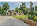 Brick house with unique arched doorways, lush green lawn, mature trees, and a concrete driveway at 4296 Linda Sw Ln, Lilburn, GA 30047