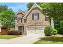Two-story brick home featuring an attached two-car garage, inviting curb appeal, and mature landscaping at 830 Nottingham Se Dr, Smyrna, GA 30082