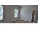 Bedroom features two large windows and beige carpet; door to closet is open at 1661 Fuma Leaf Way, Mcdonough, GA 30253