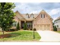 Charming brick home featuring a manicured lawn, dormer windows, and a spacious two-car garage at 2665 Crowbrook Way, Cumming, GA 30040