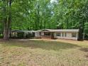 Spacious front yard showcasing a charming single-story home with a carport and a welcoming front porch nestled among trees at 85 Holly Dr, Carrollton, GA 30116