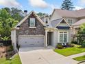 Charming home featuring a stone facade, two-car garage, and a cozy front porch with a bench at 307 Serenity Way, Woodstock, GA 30188