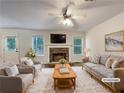 Bright living room with a stone fireplace, ceiling fan and two large windows at 6001 Deer Springs Nw Ln, Acworth, GA 30101