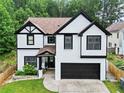 Two story home featuring a two-car garage, black trim, and manicured front lawn at 2111 Nelms Pointe Lndg, Lawrenceville, GA 30043