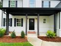 Inviting front porch with dark columns and black door, complemented by manicured landscaping at 1540 Ox Bridge Ct, Lawrenceville, GA 30043