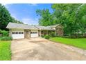 View of the home and garage with a large driveway and lawn with mature trees offering ample parking space at 486 Buttercup Trl, Lawrenceville, GA 30046