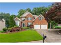 Charming two-story brick home with a well-manicured lawn, a two-car garage, and mature trees at 2026 Cresthaven Walk, Woodstock, GA 30189