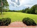 View of the expansive backyard from the brick stairs, surrounded by mature trees and lush greenery at 238 Marks Rd, Mansfield, GA 30055