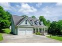 Two-story home featuring an attached two-car garage and a covered front porch, set against a backdrop of lush greenery at 410 Hendon Rd, Woodstock, GA 30188