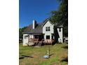 Home's rear elevation with spacious deck and stairs leading to the backyard and large mature trees at 410 Hendon Rd, Woodstock, GA 30188