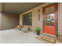 Inviting front porch featuring a vibrant orange door, brick facade, and cozy seating area at 6460 Cortland Walk, Alpharetta, GA 30005
