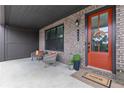 Inviting front porch features brick accents, seating, and an orange front door with a wreath at 6460 Cortland Walk, Alpharetta, GA 30005