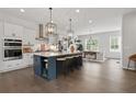 Open-concept kitchen boasts a large island with seating, pendant lighting, and stainless steel appliances at 6460 Cortland Walk, Alpharetta, GA 30005
