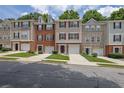 Street view of townhomes with lawns, driveways, garages, and sidewalks under cloudy blue skies at 541 Lantern Wood Dr, Scottdale, GA 30079