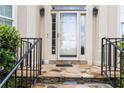 Inviting front entrance with stone steps, black iron railing, glass door, and elegant sidelights at 2280 Wildwood Lake Dr, Suwanee, GA 30024