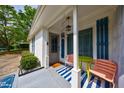 Inviting front porch with a blue striped rug, colorful chairs and charming decor elements at 1915 Cooper Landing Se Dr, Smyrna, GA 30080