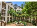 Serene condo courtyard with a central fountain, lush trees, and surrounding buildings at 472 Sherman Way, Decatur, GA 30033