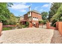Rear view of a brick house with a stone driveway, iron gate, brick columns, a wood deck and mature landscaping at 470 Manor Oak Se Ln, Marietta, GA 30067