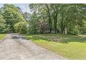 A beautiful home nestled among mature trees, showcasing a well-manicured lawn and a long driveway at 143 Cotton Mill Dr, Hiram, GA 30141
