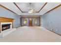 Large living room with fireplace, neutral carpet, tray ceilings, and natural light from the doorway at 2865 Bryant Ct, Cumming, GA 30040
