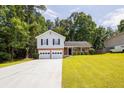 Traditional two-story home with a two-car garage, lush lawn, and mature trees at 6541 Lazy Creek Ct, Lithonia, GA 30058