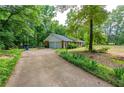 Side view of home featuring a long driveway leading to an attached garage with beautiful trees and greenery surrounding the property at 299 Fieldview Dr, Auburn, GA 30011