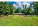 Expansive green lawn and mature trees of this one-story home offer a serene setting for comfortable living at 299 Fieldview Dr, Auburn, GA 30011